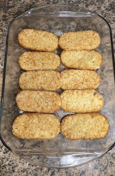 several pieces of breaded chicken in a glass dish on a granite counter top, ready to be cooked