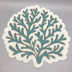 a white doily with blue and brown designs on the edges is sitting on a gray surface