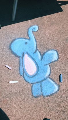 an elephant drawn on the ground next to crayons