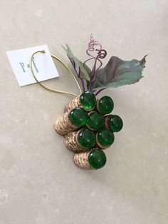 a brooch with green glass beads on it sitting on a table next to a tag