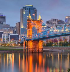 the city skyline is reflected in the water at night, with a bridge crossing over it