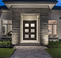 the front entrance to a house at night with lights on and brick walkway leading up to it