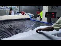 two men working on an assembly line at a fabric manufacturing facility with workers in the background