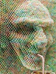 a man's face is made out of many different colored plastic bottles, with a metal faucet in the foreground