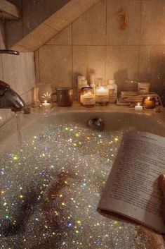 an open book sitting in the middle of a bathtub filled with water and candles