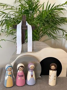 a group of wooden dolls sitting next to a potted plant