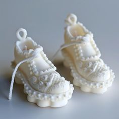 two miniature white shoes with lace on them