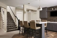 a kitchen and dining room with stairs leading up to the second floor that has a tv on the wall