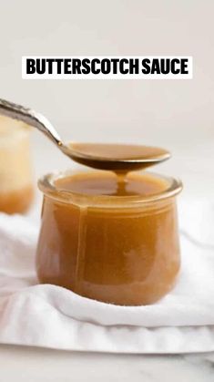 a spoon full of peanut butter sitting on top of a white cloth next to a jar