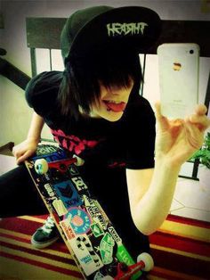 a person sitting on the ground with a skateboard in their hand and wearing a hat