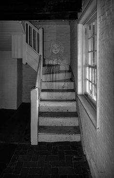 an old building with some stairs leading up to the second floor and a painting on the wall