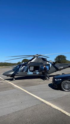 a black car is parked next to a helicopter