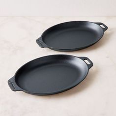 two black frying pans sitting on top of a counter