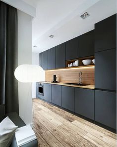 a modern kitchen with black cabinets and wood flooring