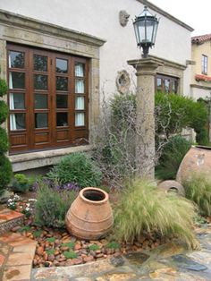 a stone walkway leads to a house with large pots and plants in the front yard