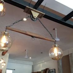 three light fixtures hanging from a ceiling in a room with wood beams and glass globes