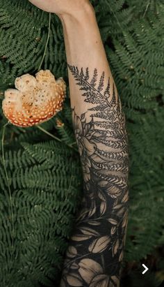 a person's arm with a tattoo on it next to some plants and flowers