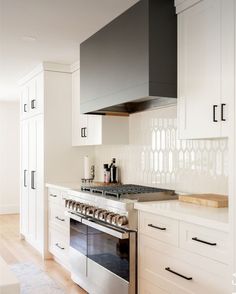 a kitchen with white cabinets and stainless steel stove top oven in the center of the room