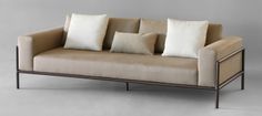 a couch with four pillows on it sitting in front of a gray wall and floor