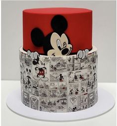 a mickey mouse cake with comic pages on it's bottom and the top layer is red