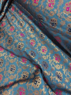 a blue and gold floral print fabric with pink flowers on the bottom half of it