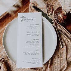 a white plate topped with a menu on top of a wooden table next to utensils