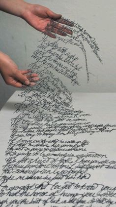 two hands are writing on an old paper with cursive writing and inking