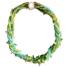 Natural gems from the Earth inspired this necklace. Strands of green peridot and blue aquamarine reflect earth and sky. Woven throughout are sparkling multi size faceted pear-shaped pale aquamarine briolettes glistening like new fallen raindrops . The faceted beads and most especially the briolettes subtly glitter with every movement. The necklace is finished with a 14kt gold open oval clasp pave with tiny white diamonds. Length: 17 1/2” Style: Contemporary Date: 2020 Creator: Ned Marshall Green Gemstone Beads Fusion Necklace, Green Fusion Style Gemstone Beads Necklace, Green Gemstone Fusion Necklace, Handmade Green Briolette Jewelry, Green Fusion Style Gemstone Necklace, Green Teardrop Faceted Beads Jewelry, Green Teardrop Faceted Necklace, Green Teardrop Necklace With Faceted Beads, Green Faceted Briolette Necklaces