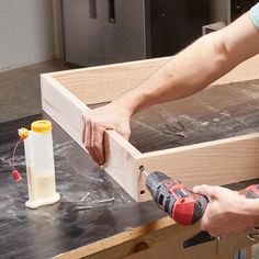 a man using a power drill to attach a piece of wood on top of a table