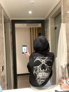 a person taking a selfie in a bathroom mirror with a skull on it's back