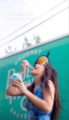 a woman eating food out of a plastic container while standing in front of a truck