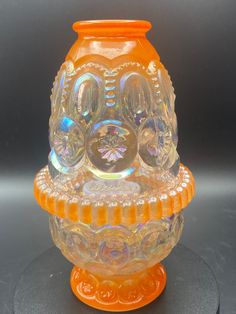 an orange glass vase sitting on top of a table