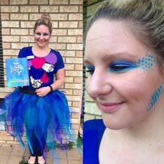 a woman with blue and purple makeup is smiling at the camera while holding a book