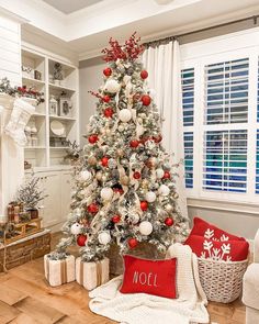 a decorated christmas tree in the corner of a living room with red and white ornaments