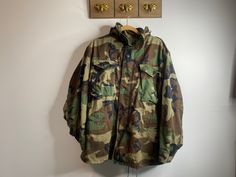 "1960s US ARMY lined camo military jacket / cold weather coat by John Ownbey Co. Inc. Vintage, Vietnam era military issued cold-weather lined coat with hood.  Please note this is a Vintage item and does show signs of wear such as discolorations and loose threads. Most notable is staining on the right front bottom pocket. Please view photos. In overall good vintage condition.  50% cotton, 50% polyester. Metal zipper.  Concealable zippered hood. Velcro on sleeve cuffs. Shoulder epaulettes.   Size Vintage Camouflage Hunting Outerwear, Vintage Camouflage Outerwear For Hunting, Vintage Camouflage Winter Outerwear, Vintage Camouflage Outerwear For Outdoor, Vintage Camouflage Outerwear For Fall, Military Style Hunting Parka For Fall, Winter Military Utility Jacket For Hunting, Military Parka For Hunting In Fall, Military Style Parka For Fall Events