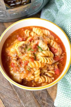 a bowl of pasta soup next to an instant pressure cooker on a wooden table