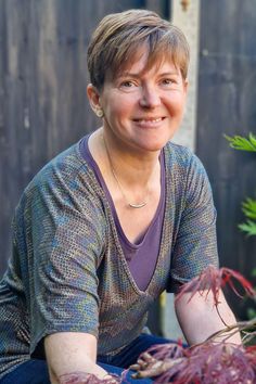 a woman sitting on the ground next to some plants