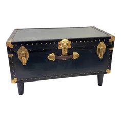 a black trunk with gold trimmings and studding on the top is sitting in front of a white background