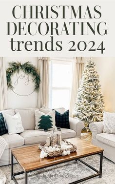 a living room with white couches and christmas decorations on the table in front of it