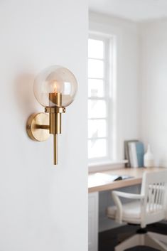 a wall light that is on the side of a wall next to a desk and chair