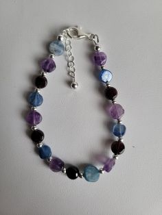 This bracelet features small flat and round coin-shaped gemstone beads. The gemstones are Amethyst (purple), Garnet (red) and Kyanite (blue). In-between each gemstone are small round sterling silver beads. It has a 1" sterling silver beaded extension and lobster claw clasp.  Custom Orders are always welcome! Most bracelets can be sized for free upon request. Adjustable Polished Beads Crystal Bracelet, Adjustable Polished Bead Crystal Bracelet, Round Crystal Bracelet With Natural Stones, Adjustable Round Crystal Bracelet With Polished Beads, Spiritual Faceted Beaded Bracelets, Purple Gemstone Beads Sterling Silver Jewelry, Faceted Round Crystal Bracelet, Amethyst Stone Bracelets, Healing Beaded Bracelets With Stones