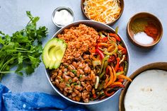 a bowl filled with beans and vegetables next to tortillas, avocado and sour cream