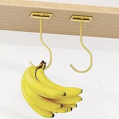 three bananas hanging from hooks on a wall