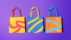 three colorful shopping bags sitting next to each other on a purple and blue background,