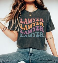 "Comfort Colors Lawyer T-shirt, Retro Lawyer Tee, Gift for Lawyer, Custom Lawyer Shirt, Tshirt for Lawyer, Womans Tee Shirt https://toptrendtshirtsus.etsy.com NOTE: Please contact me for more size,color, product (sweatshirt, hoodies,kids etc) options. I'm always here to help. Unisex Garment-Dyed T-shirt Comfort Colors® 1717 *Medium fabric (6.1 oz/yd² (206.8 g/m *Relaxed fit *Sewn-in twill label *100% ring-spun cotton About Comfort Colors introduces its garment-dyed t-shirt; a fully customizable tee made 100% with ring-spun cotton. The soft-washed, garment-dyed fabric brings extra coziness to your wardrobe while the relaxed fit makes it an excellent daily choice. The double-needle stitching throughout the tee makes it highly durable while the lack of side-seams helps the shirt retain its tu Trendy Multicolor T-shirt With Text Print, Multicolor Short Sleeve T-shirt With Screen Print, Multicolor Pre-shrunk Graphic Tee, Multicolor Graphic Tee T-shirt, Vintage Multicolor T-shirt With Letter Print, Multicolor Retro Tops With Letter Print, Multicolor Letter Print Tops With Relaxed Fit, Graphic Tee With Text Print And Crew Neck, Vintage Style Tri-blend Tops With Letter Print