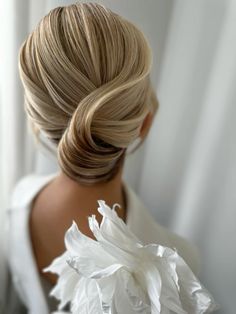 a woman with blonde hair wearing a white flower in her hair