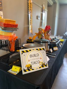 a black table topped with lots of plates and bowls filled with food next to a sign that says build your own taco