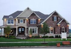 a large brick house with lots of windows and lights on it's front porch