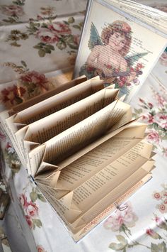 an open book sitting on top of a floral covered table cloth next to other books