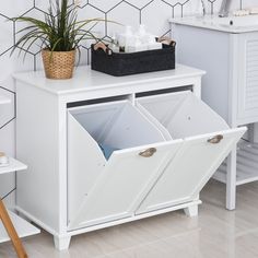 a white cabinet with two bins and a potted plant